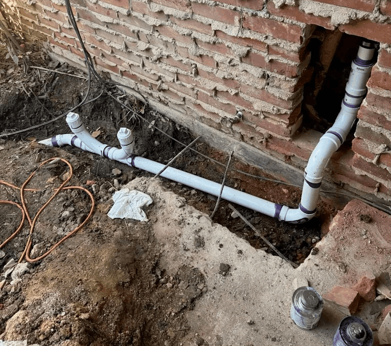 PVC drain reroute along brick exterior wall showing non-invasive plumbing repair
